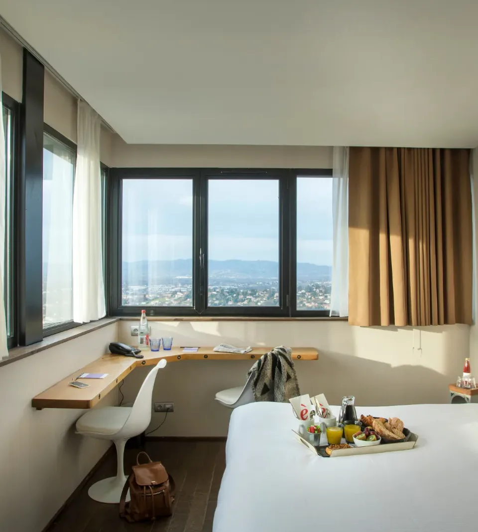 Chambre d'hôtel lumineuse avec vue panoramique sur la ville.